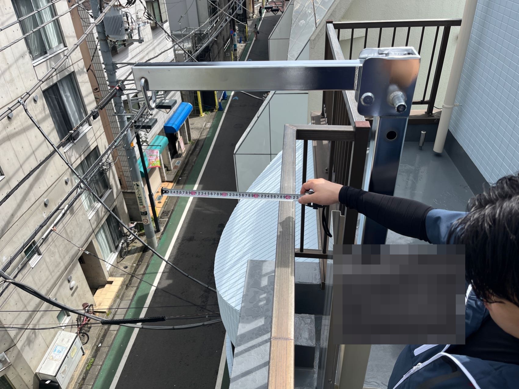 緩降機の降下位置が壁面から150mm以上300mm以下の基準内であることをメジャーで実測している様子
