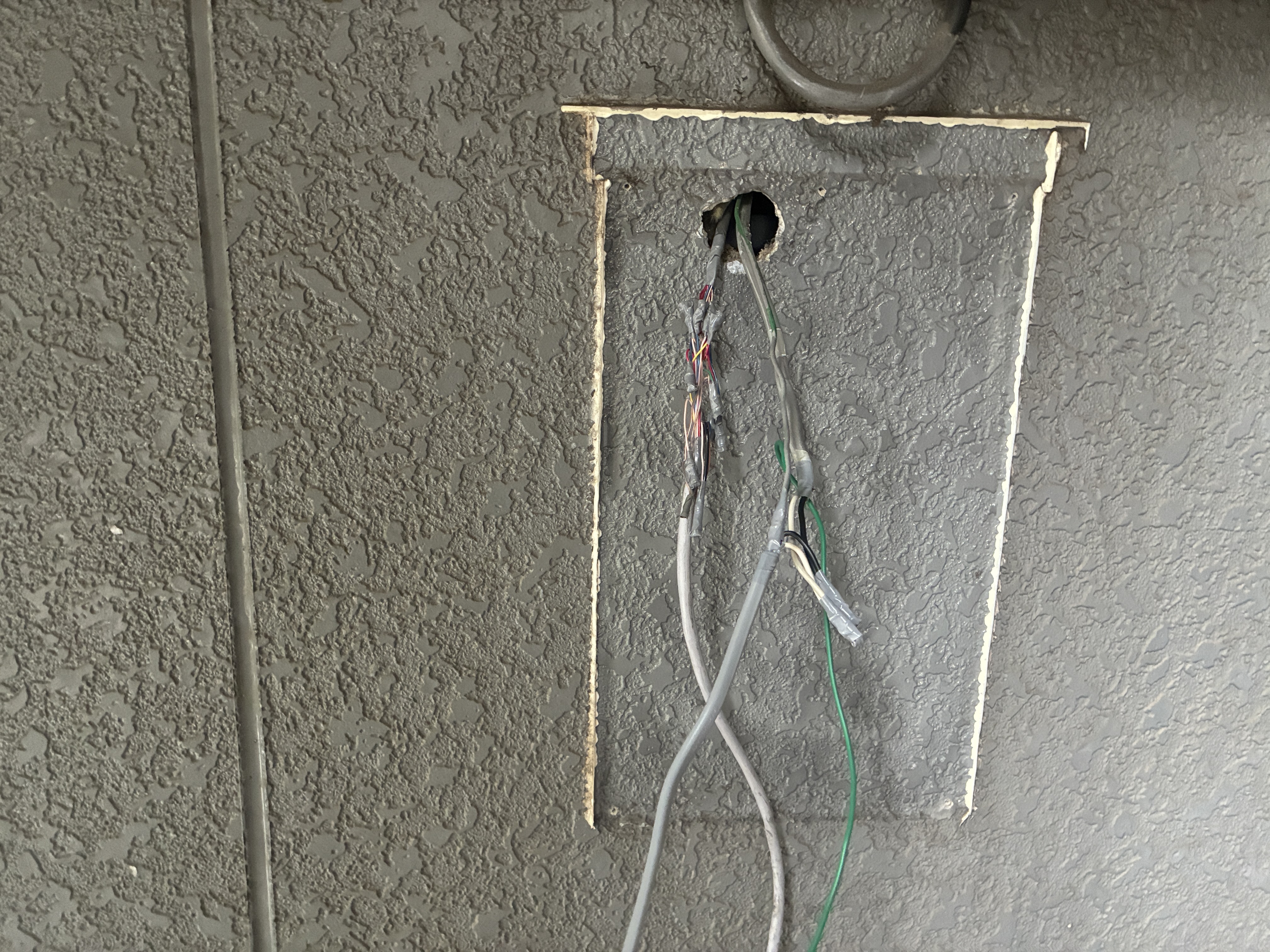 旧火災受信機を撤去した直後の壁面開口部。天井裏から下りてくる感知器回線と電源線が残っている