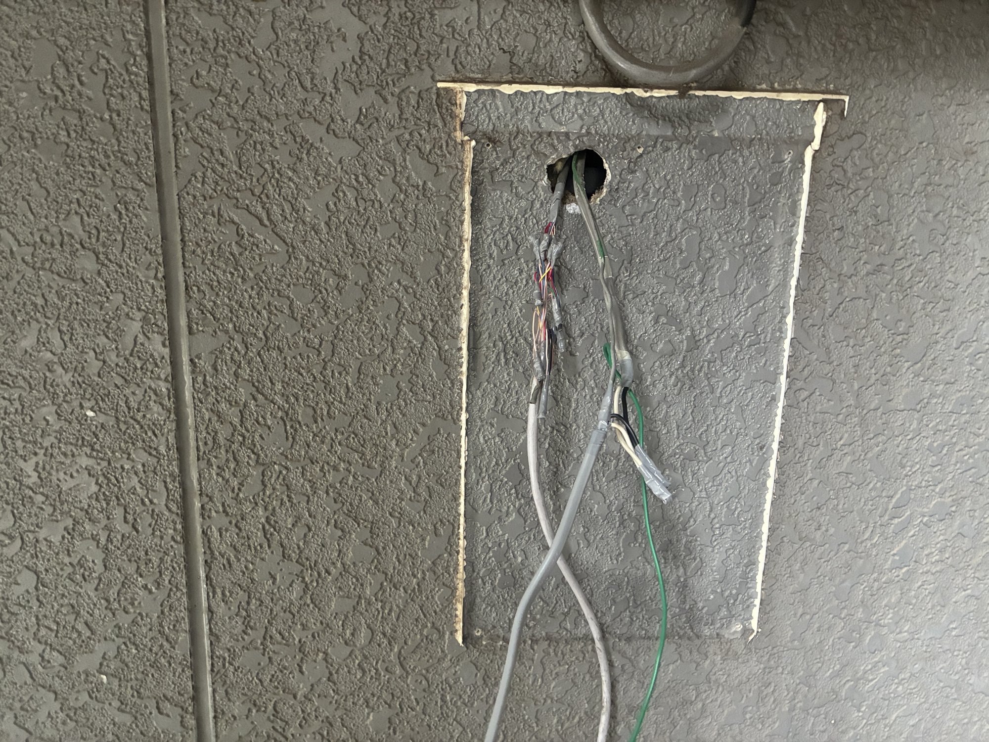 旧火災受信機を撤去した直後の壁面開口部。天井裏から下りてくる感知器回線と電源線が残っている