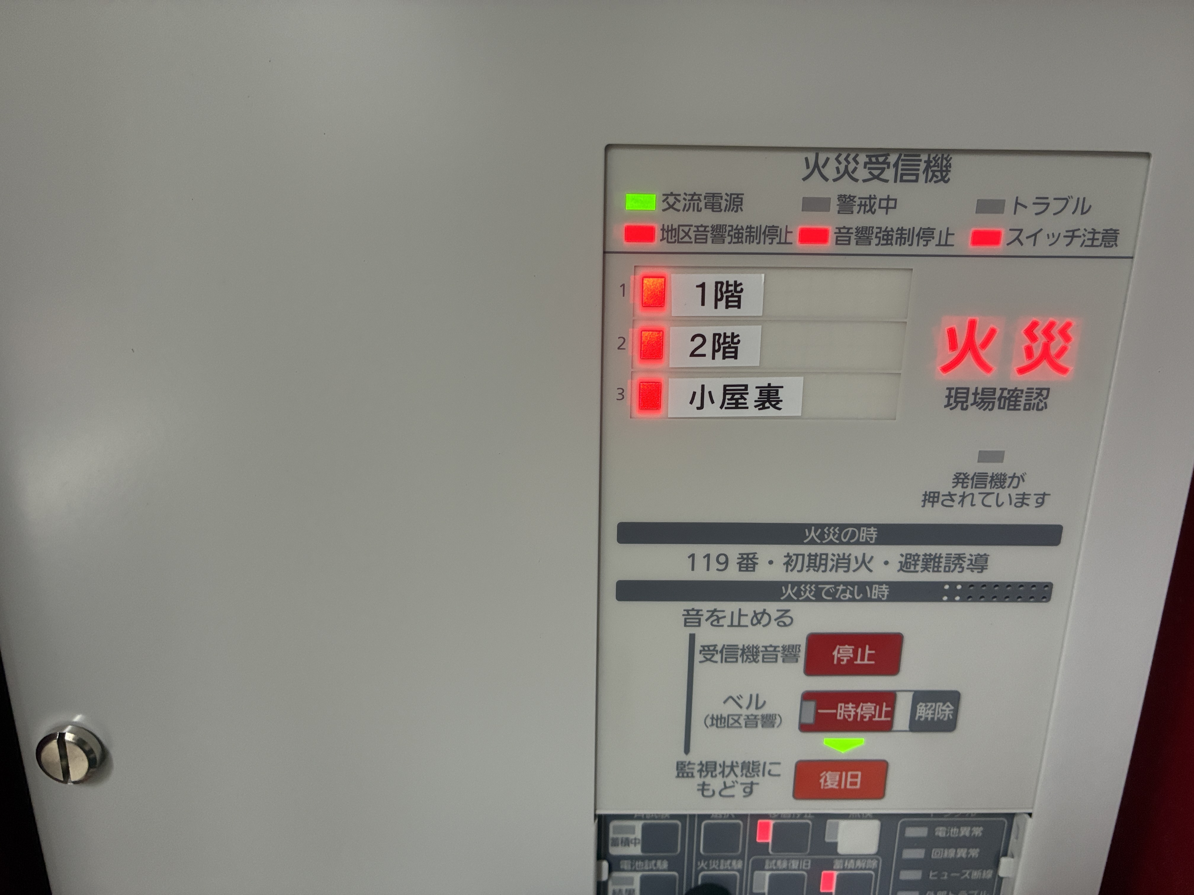 新しい火災受信機の表示部。交流電源ランプが緑に点灯し、1階・2階・小屋裏の各回線で火災表示の動作試験を行っている