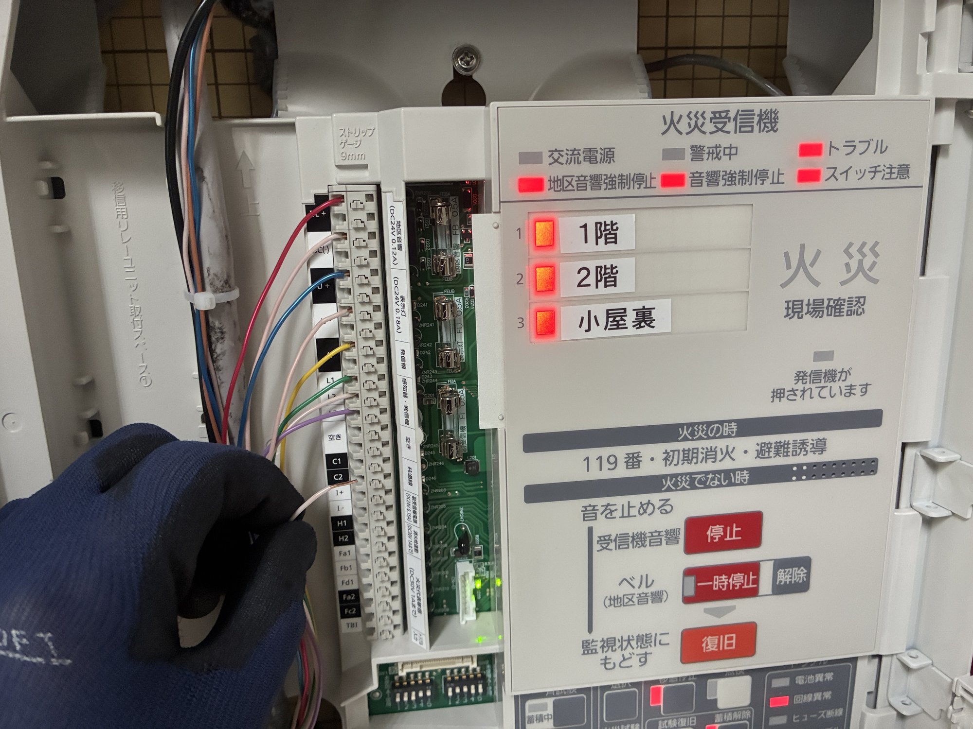 新しい火災受信機の表示部。交流電源ランプが緑に点灯し、1階・2階・小屋裏の各回線で火災表示の動作試験を行っている