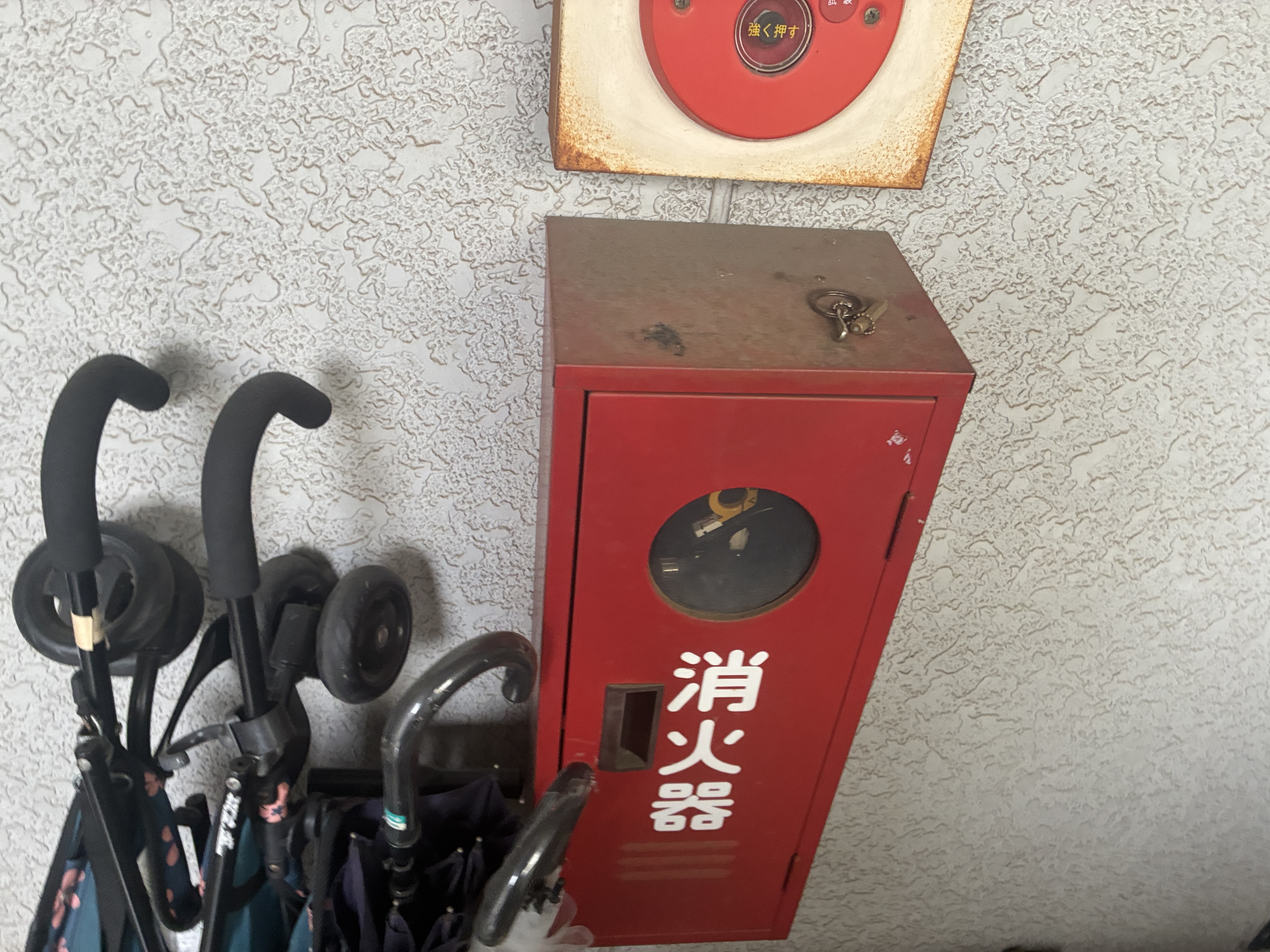 交換前のスチール製消火器格納箱。扉や天板に錆が広がり、上部の旧総合盤にも錆が出ている（東京都板橋区・築33年の共同住宅）