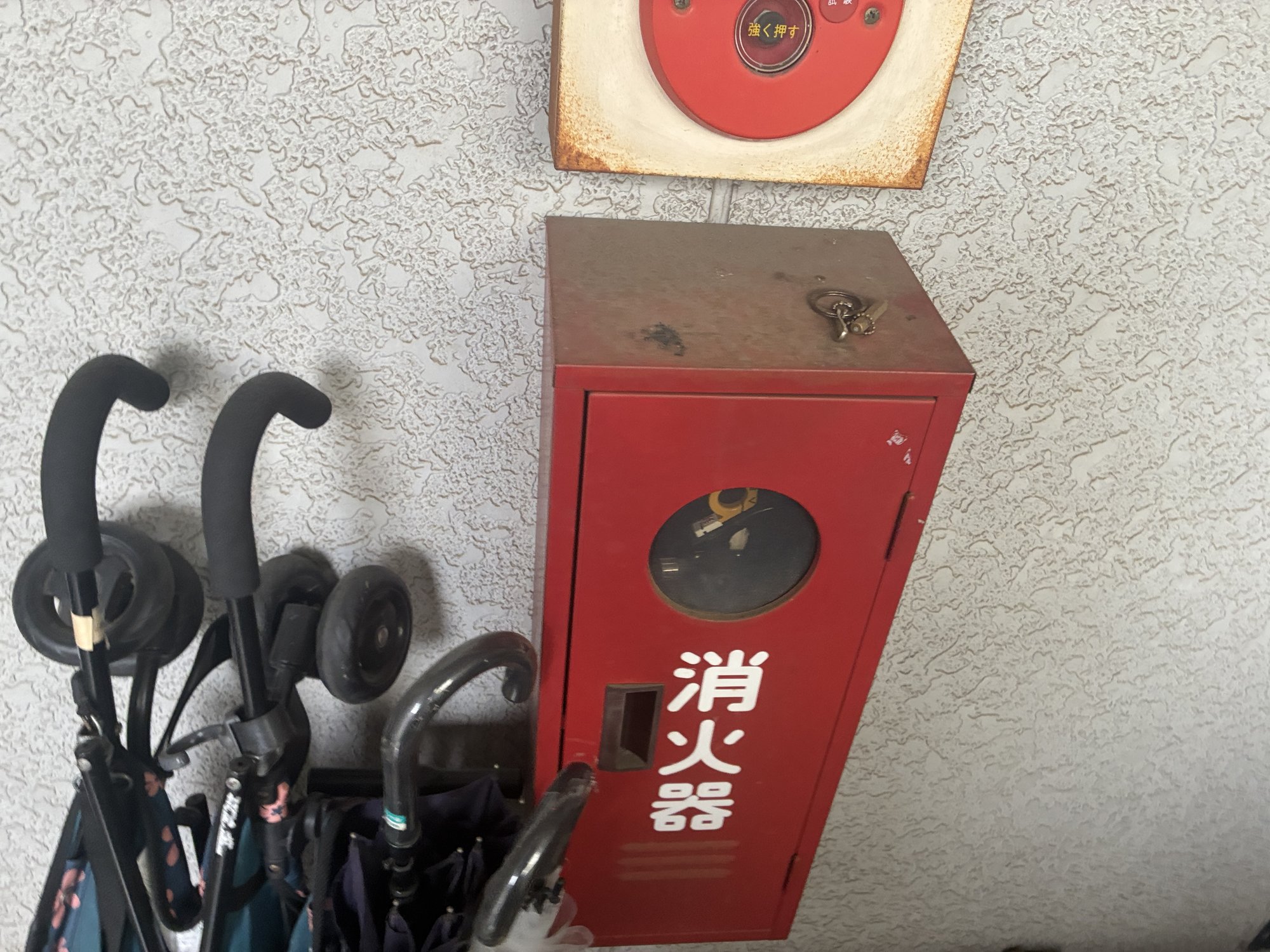 交換前のスチール製消火器格納箱。扉や天板に錆が広がり、上部の旧総合盤にも錆が出ている(東京都板橋区・築33年の共同住宅)
