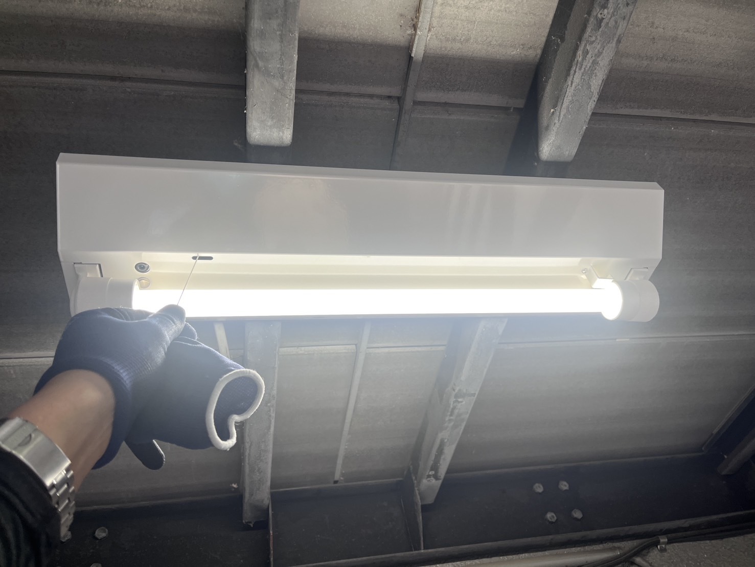 交換後のLED非常灯（富士型器具）。点検用のひもを引いて非常点灯を確認している
