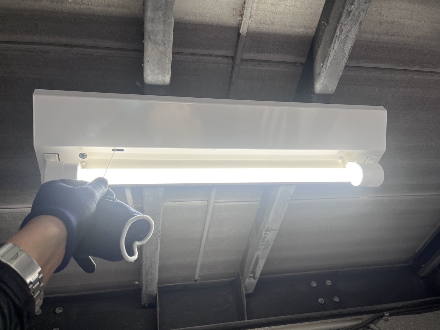 交換後のLED非常灯(富士型器具)。点検用のひもを引いて非常点灯を確認している