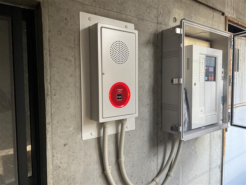 交換後の防雨型総合盤と、格納箱に収めた火災受信機（共用部分の外壁）