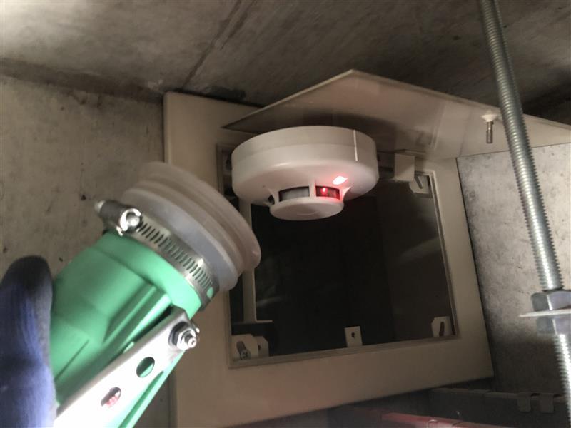 エレベーターシャフト上部の光電式スポット型感知器（煙感知器）の加煙試験の様子