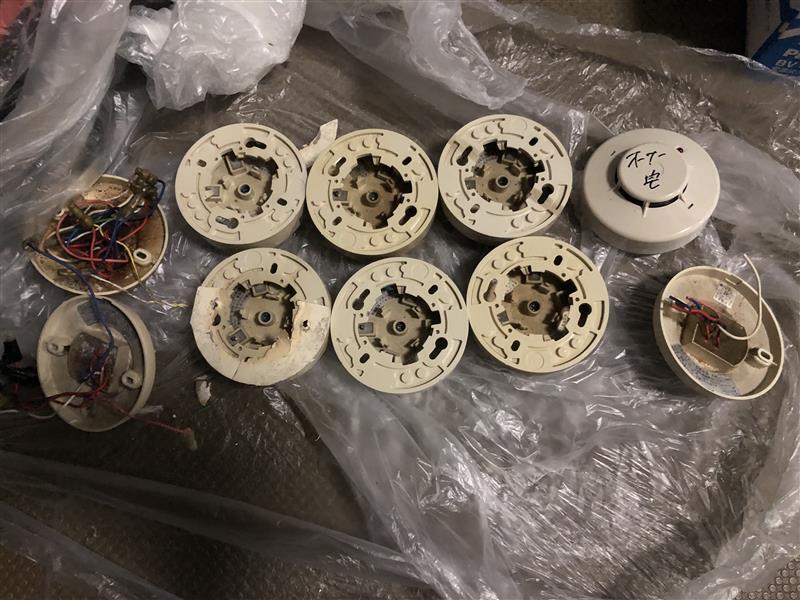 交換のため取り外した経年劣化した火災感知器。樹脂ベースが割れているものもある（東京都新宿区の共同住宅）