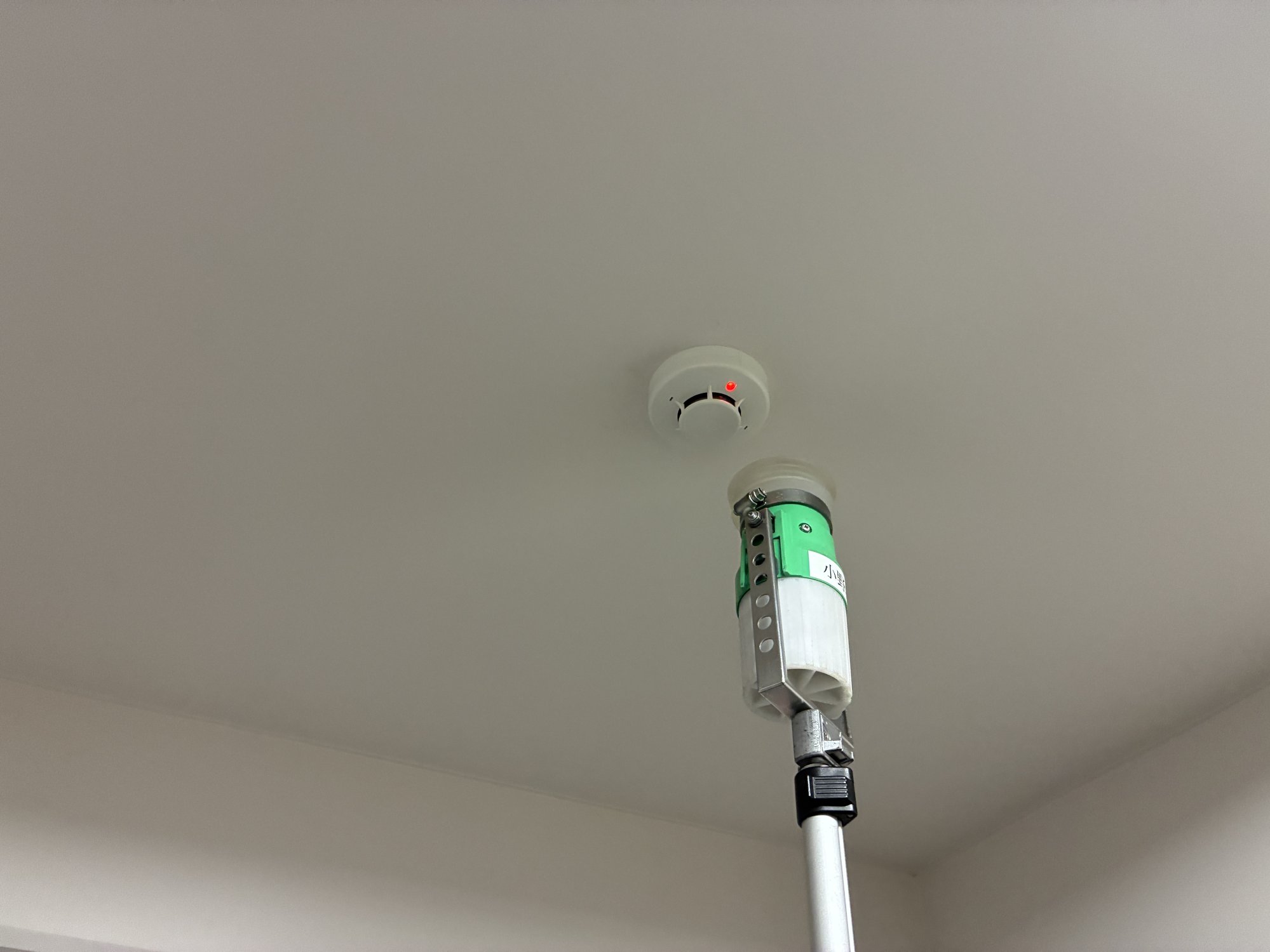 交換後の光電式煙感知器を加煙試験器で試験している様子