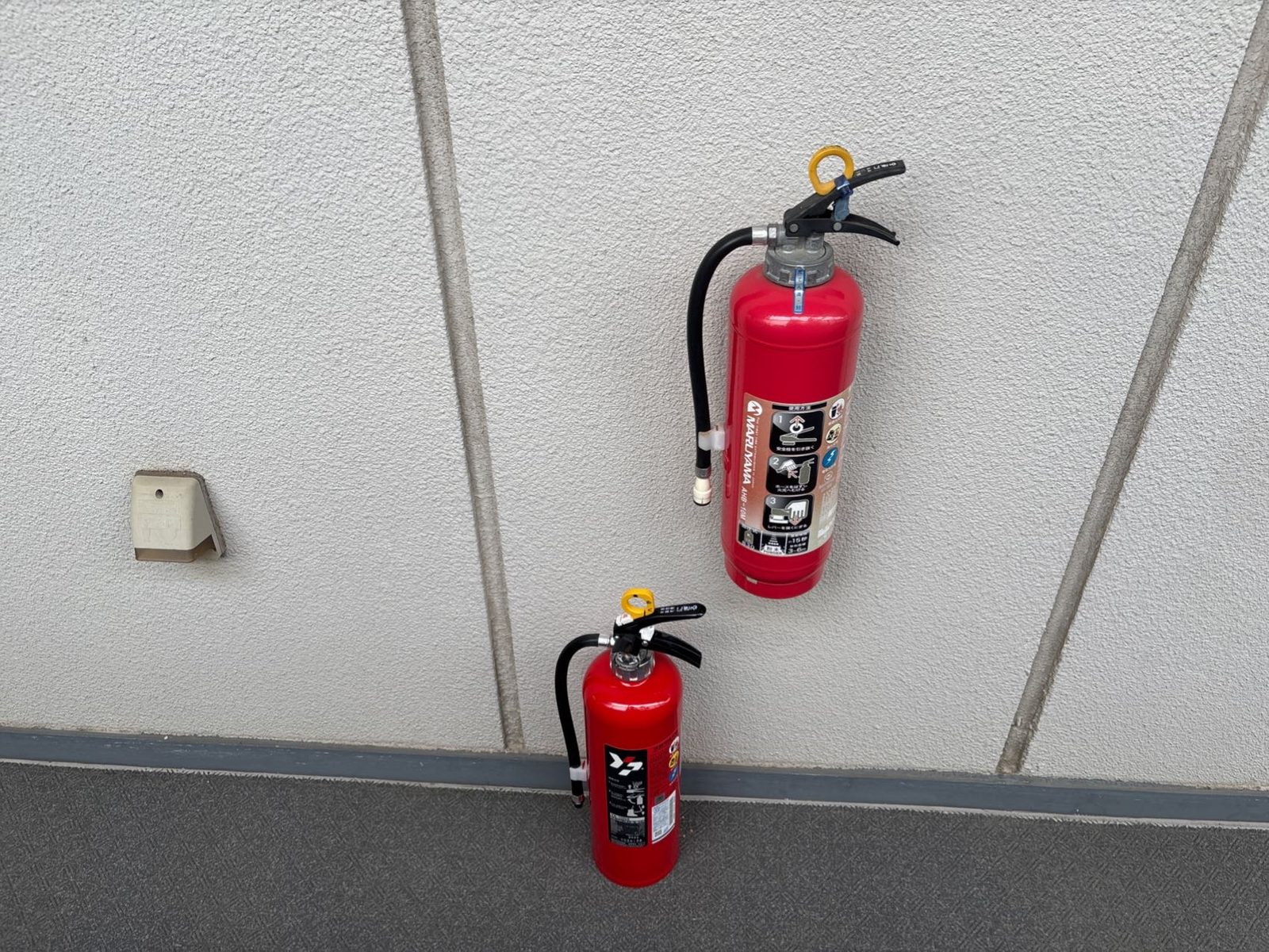 消火器交換中の様子。壁に掛かった交換前の消火器の下に、新しい粉末ABC消火器を用意している