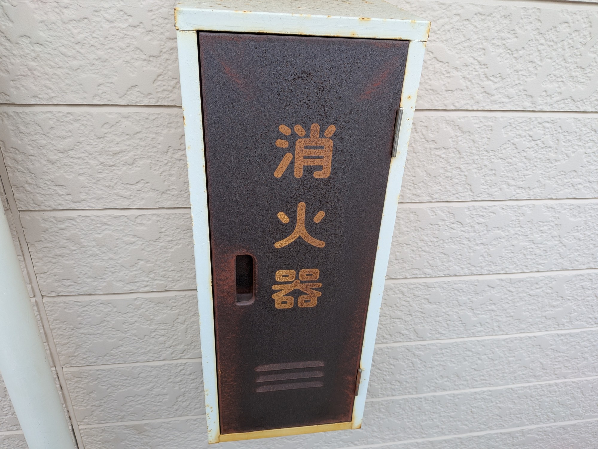 交換前のスチール製消火器格納箱。扉全体が茶色く錆び、「消火器」の文字も変色している