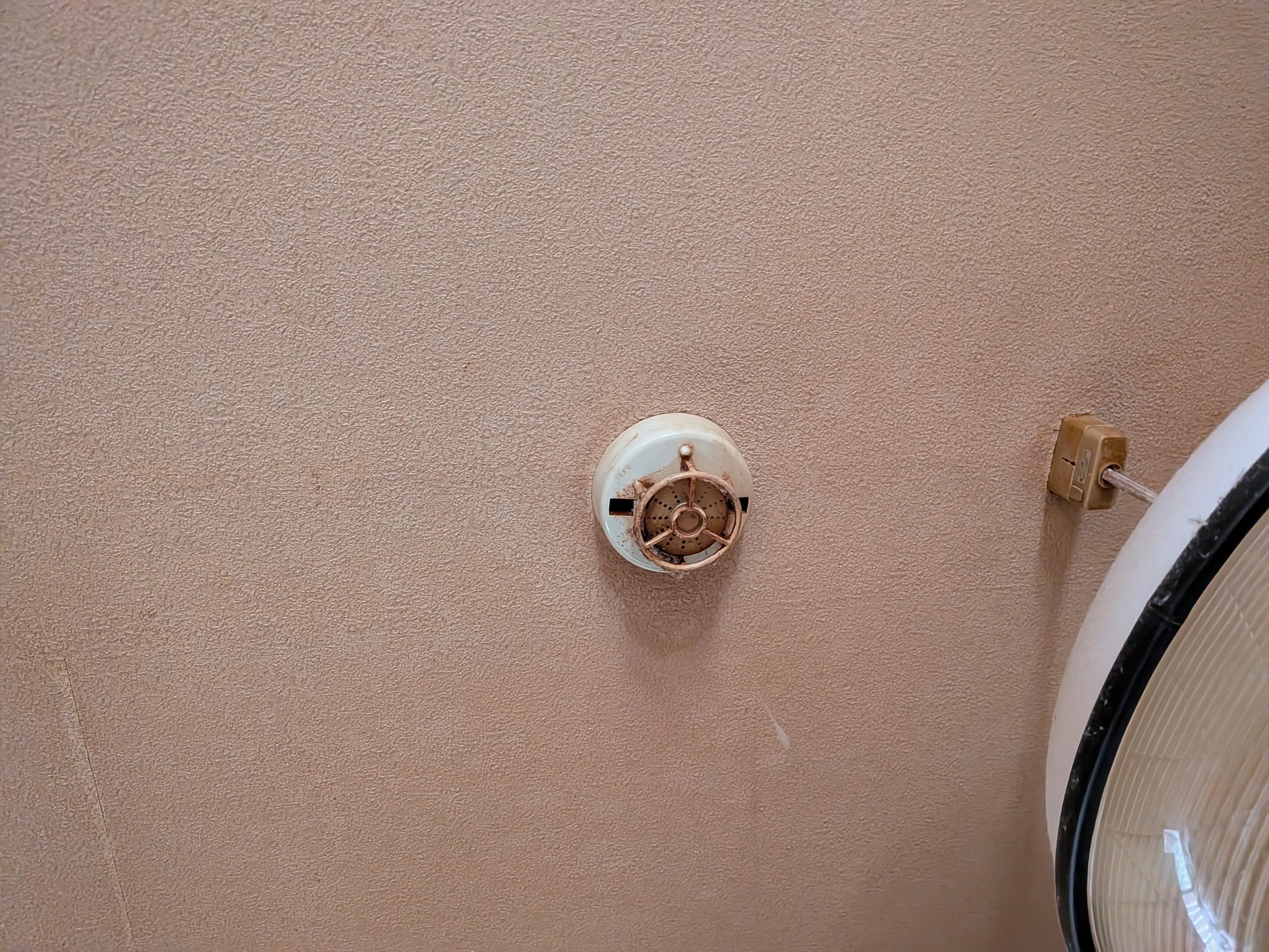 交換前の定温式スポット型感知器。感熱部の金具が錆び、ベースも変色している