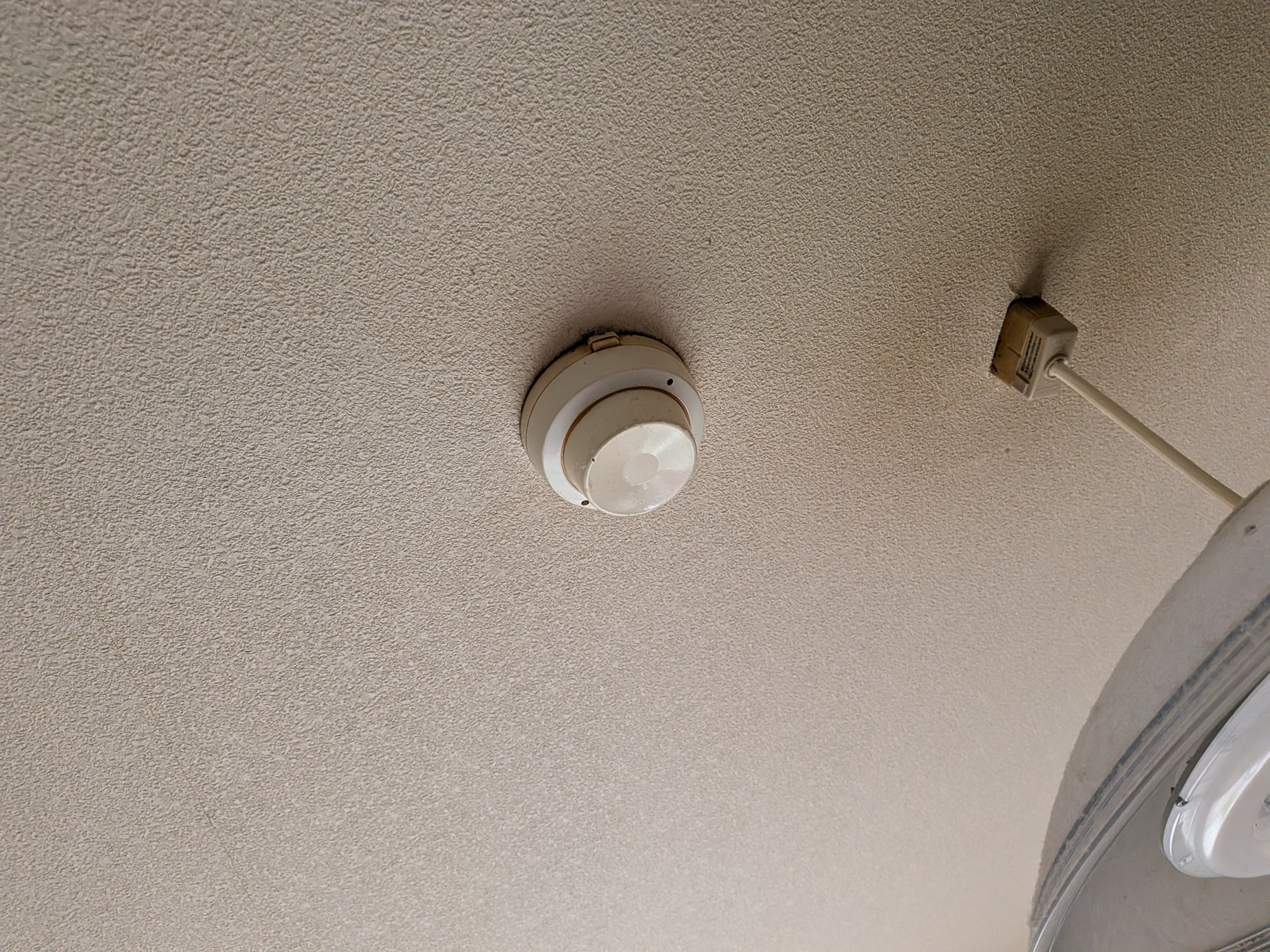 交換前の差動式スポット型感知器。本体が黄ばみ、ベースとの境目に汚れが溜まっている