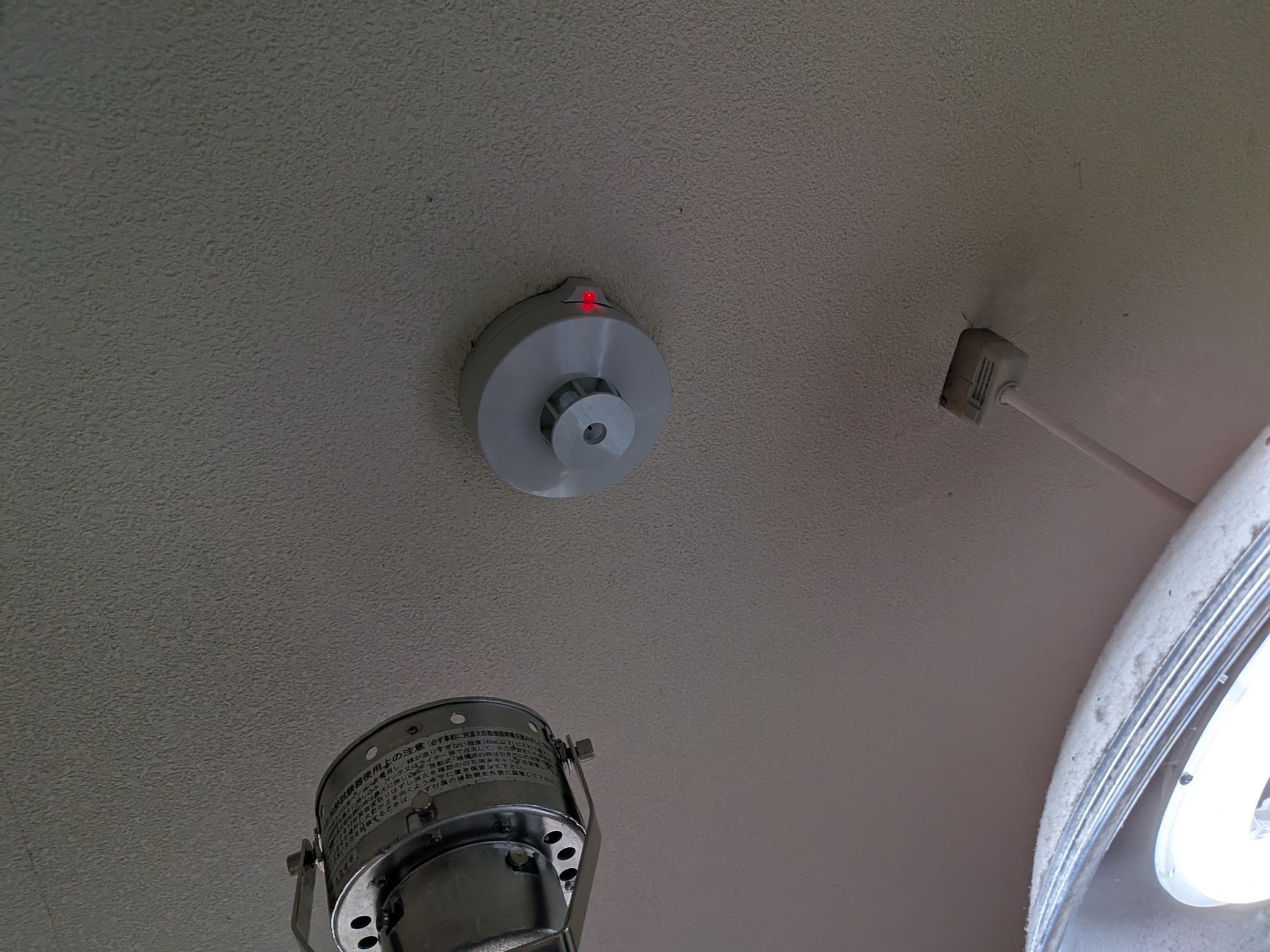 交換後の感知器に加熱試験器をあて、作動灯が赤く点灯しているところ