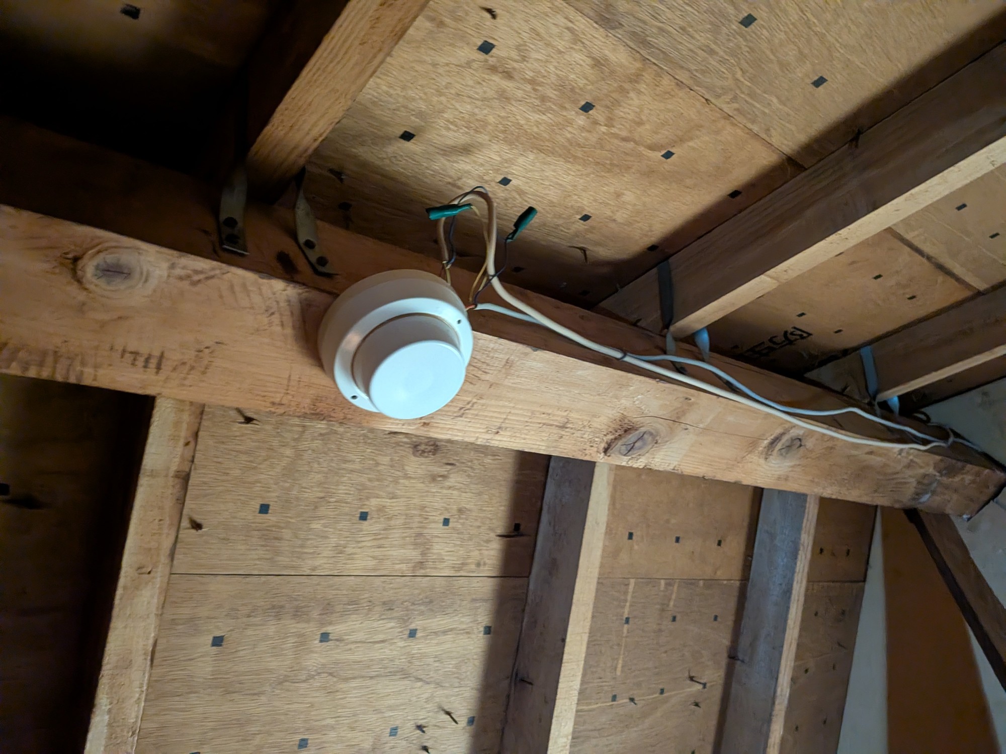 小屋裏の梁に取り付けた新しい感知器。既存配線と新しい感知器の電線を接続している
