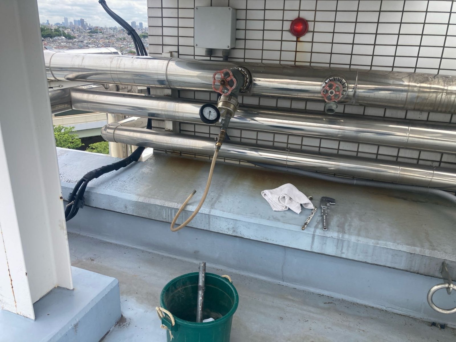 屋上の連結送水管の末端部に圧力計を取り付けて末端側の圧力を確認している様子