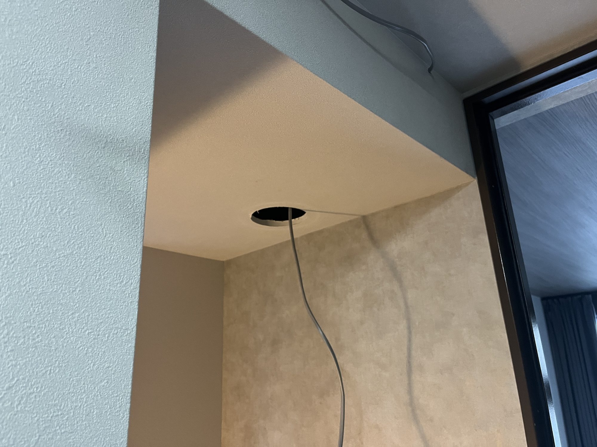 旅館（B棟）の下がり天井に開けた配線用の開口部から誘導灯の電源ケーブルを引き出しているところ