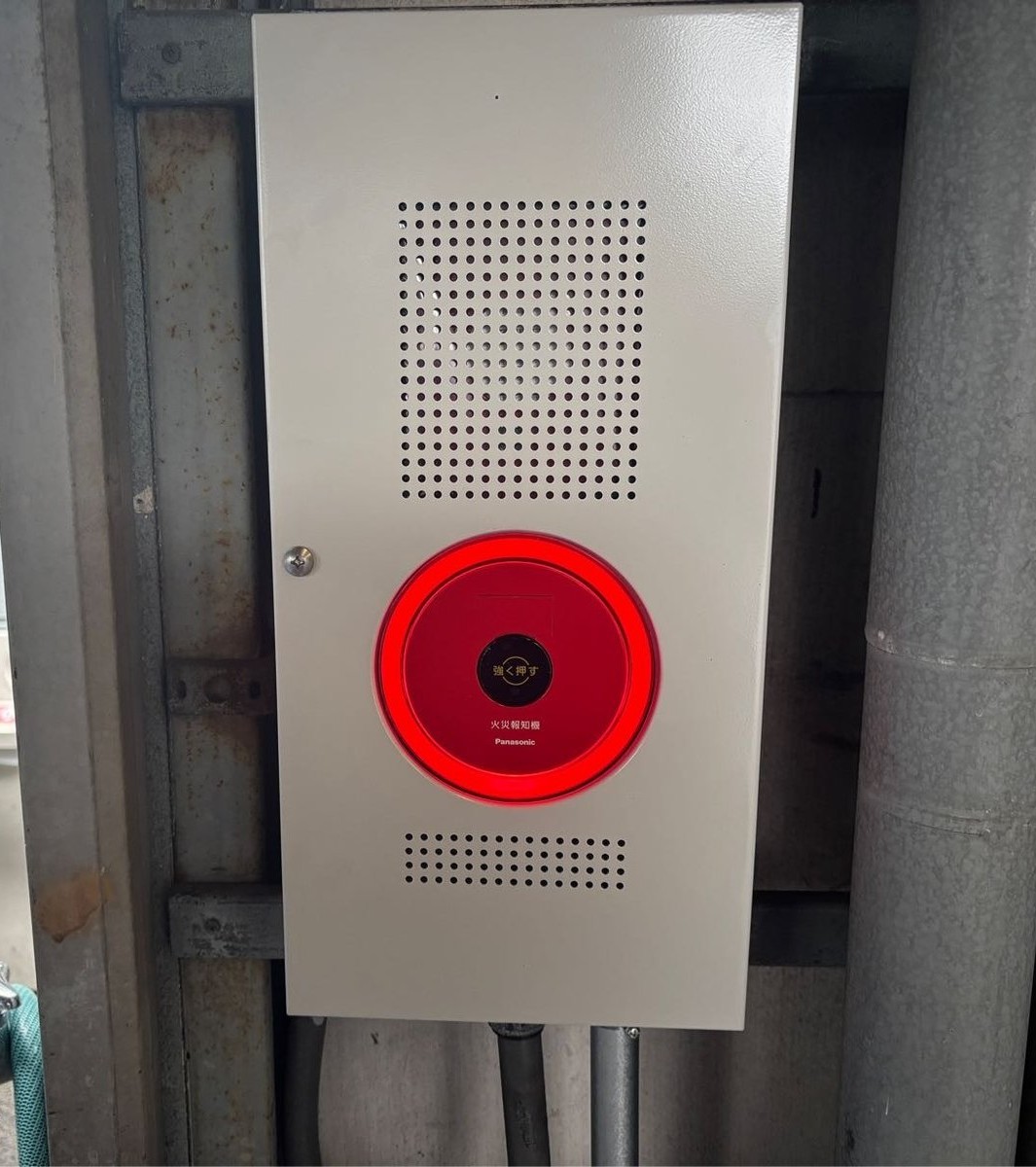 交換後の屋外用発信機総合盤。パナソニック製で、表示灯がリング状に赤く点灯している