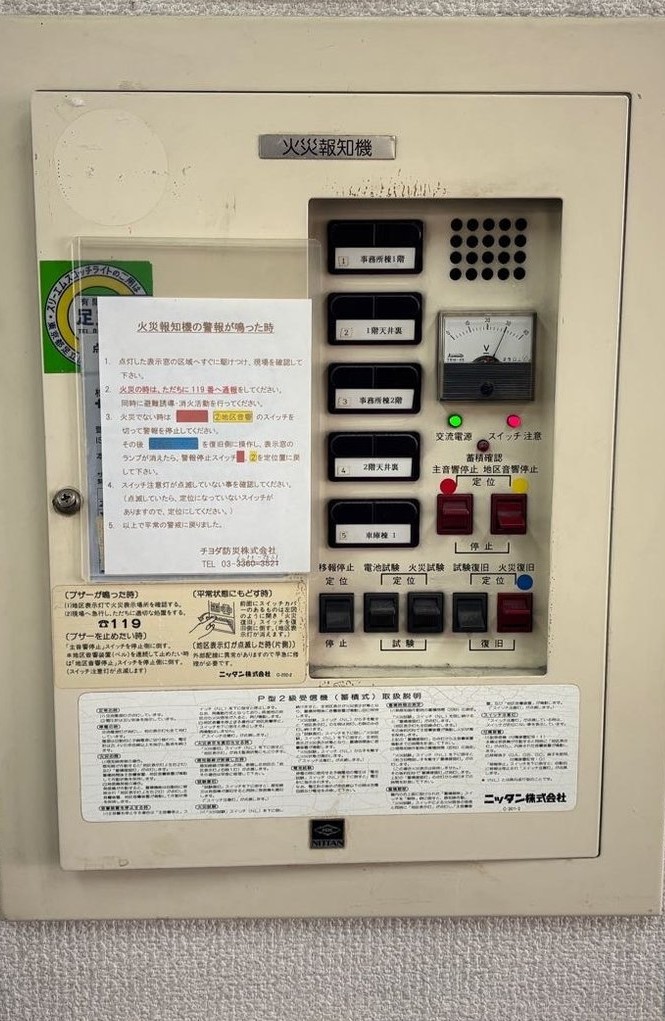 埼玉県春日部市の事業所に設置されていた1993年製の旧火災受信機。P型2級受信機で、扉を開けると操作スイッチと電圧計が並ぶ
