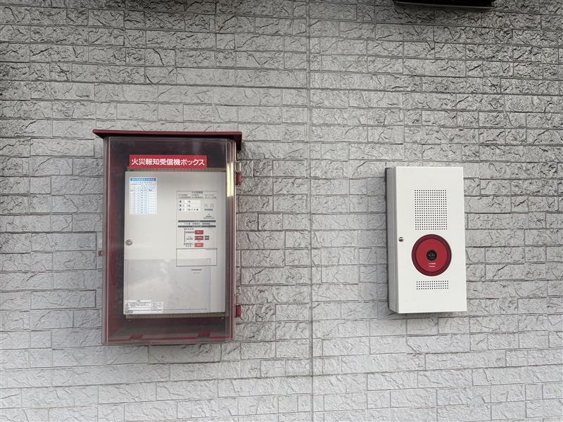 屋外の壁面に設置された火災報知受信機ボックスと発信機