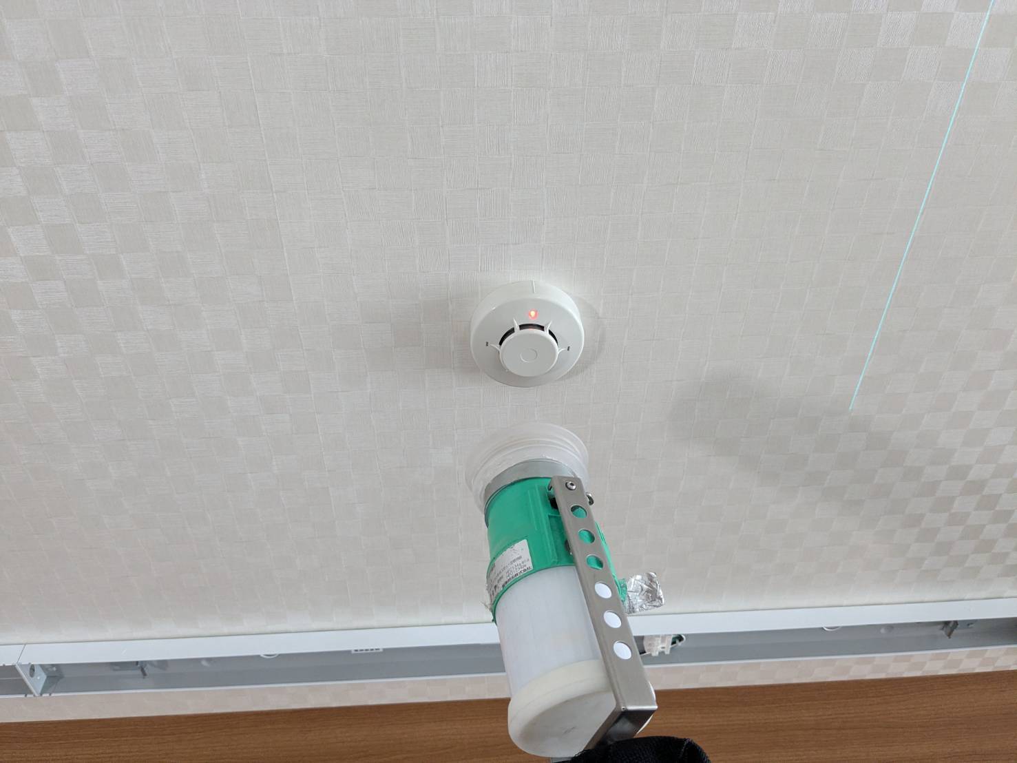 増設した煙感知器の加煙試験。試験器で煙を当てて作動を確認している