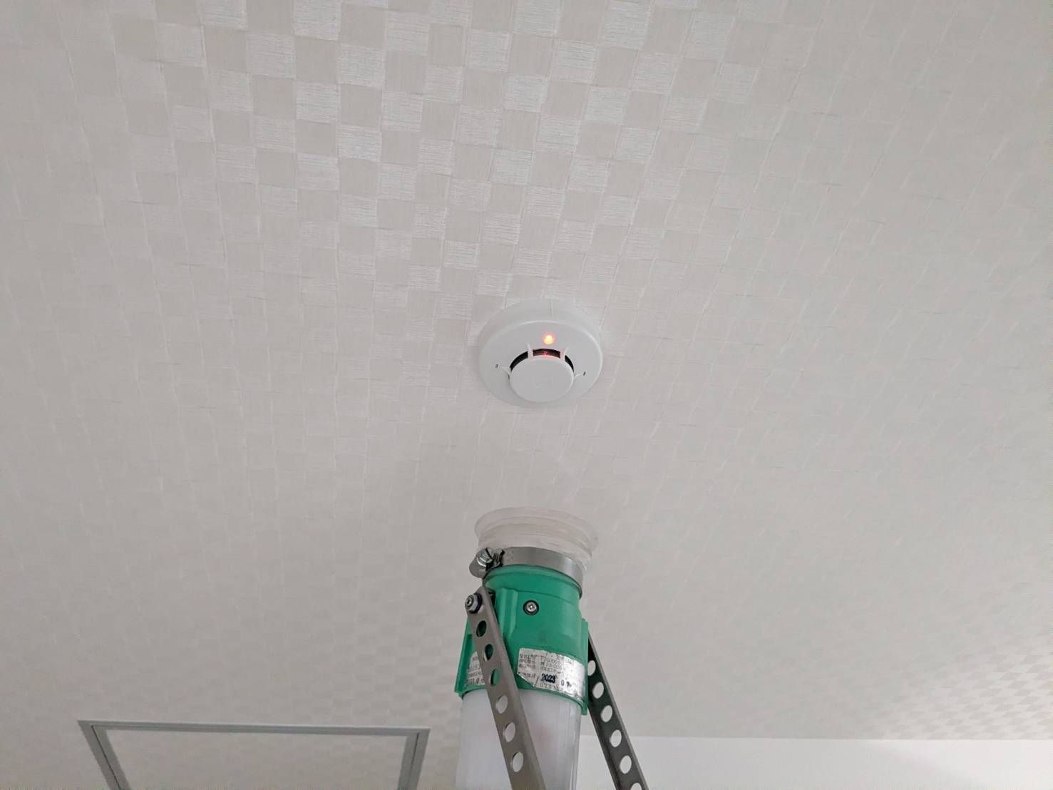 増設した光電式煙感知器の作動確認。表示灯が赤く点灯している