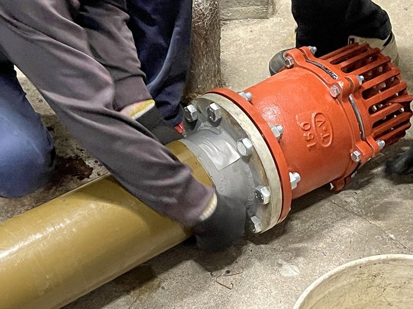 新しい吸水管の端にフート弁をフランジで接続したところ。ボルトとナットで固定されている