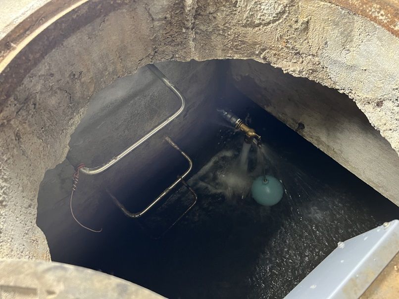 交換後のボールタップ。新しい真鍮製の弁から水が勢いよく出ており、緑色の樹脂製の浮き玉が浮いている