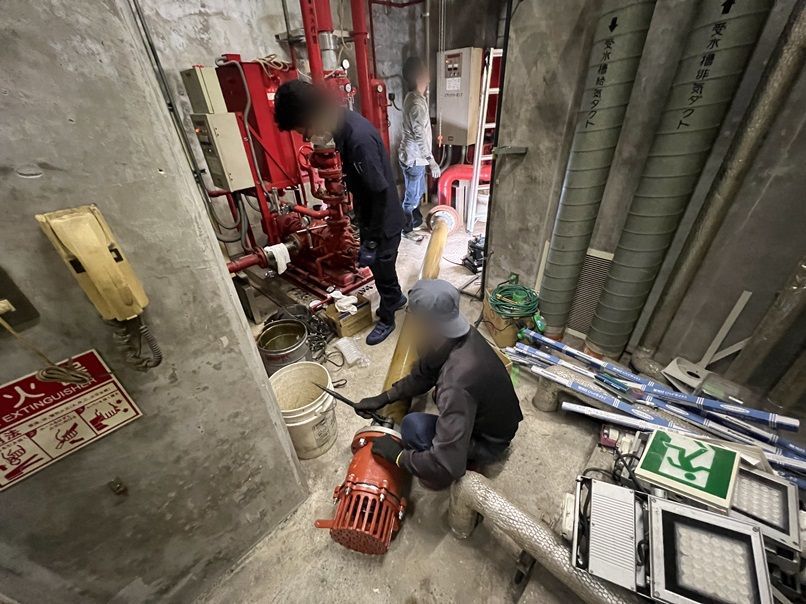 ポンプ室の床に置いた新しいフート弁と新しい吸水管。作業員が取り付けの準備をしている
