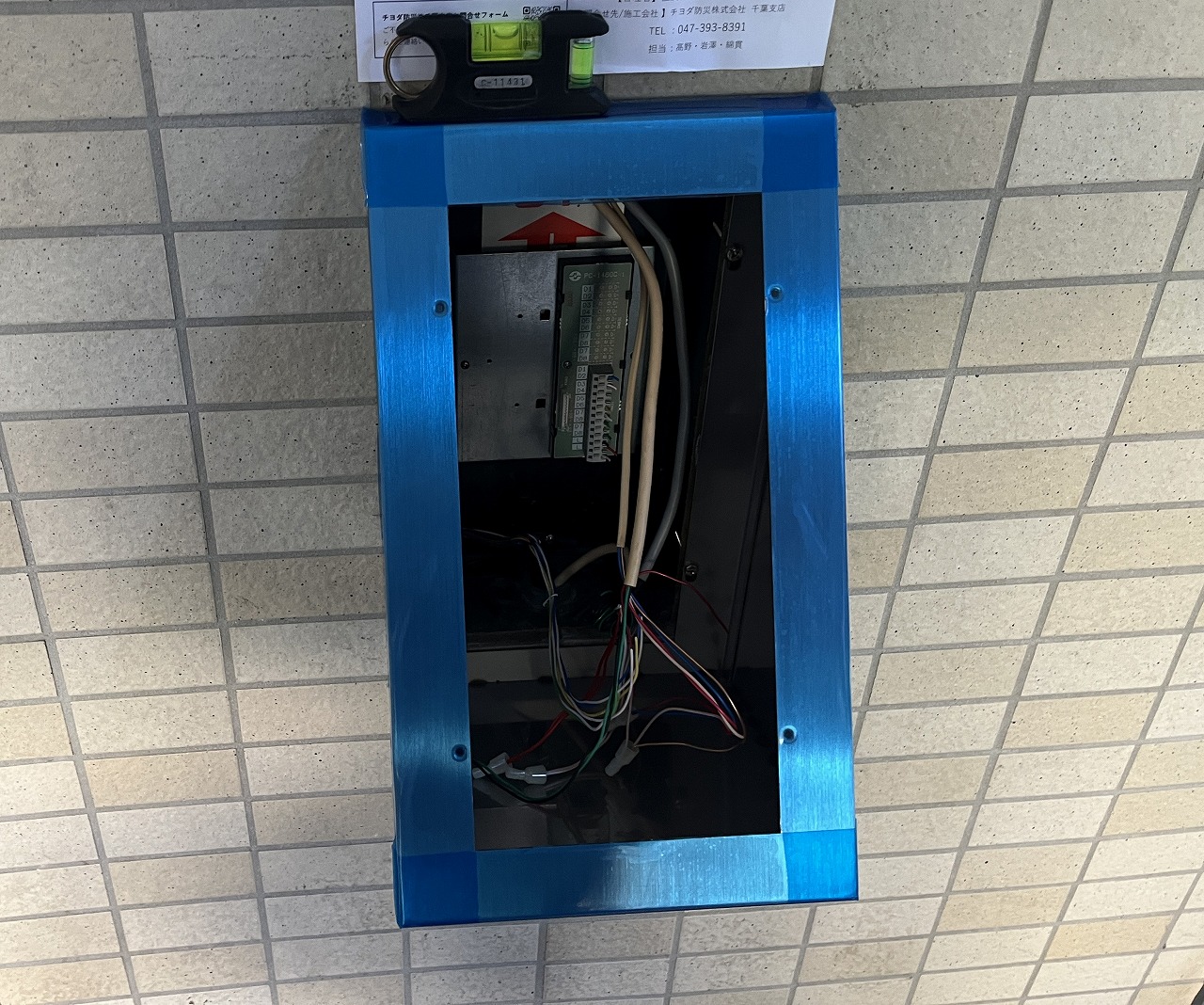 水平器で確認しながら新しい集合玄関機を取り付ける様子