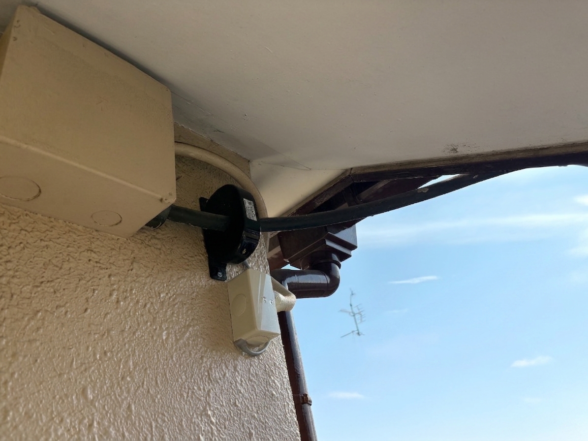 交換後の漏電火災警報器の変流器。軒下の引込線に黒い屋外型変流器を取り付け、信号線を接続ボックスに引き込んでいる