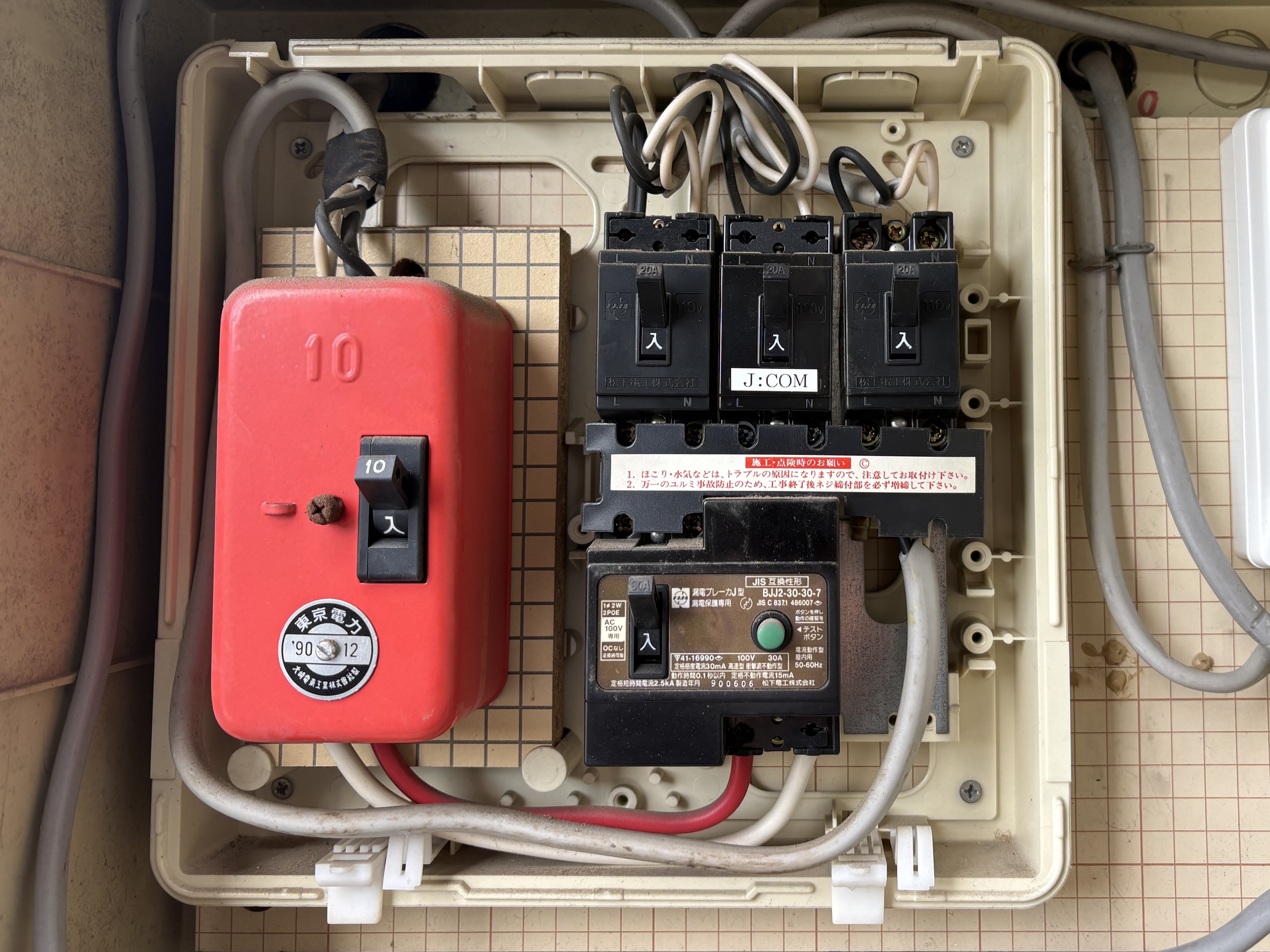 分電盤のカバーを外した内部。東京電力の1990年12月のシールが貼られた電流制限器、20Aの分岐ブレーカー3個、30Aの漏電ブレーカー