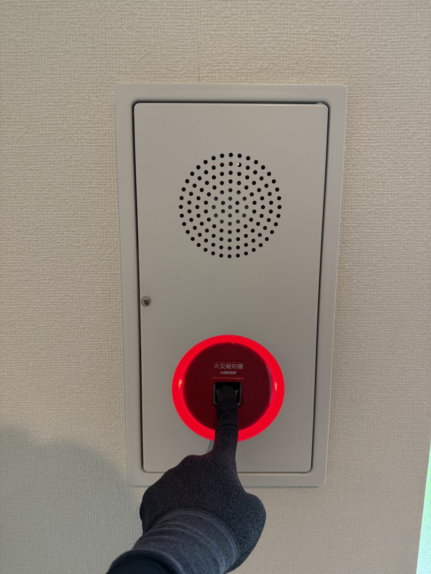 壁の総合盤。下部の発信機の赤い枠が光り、ボタンが押された状態