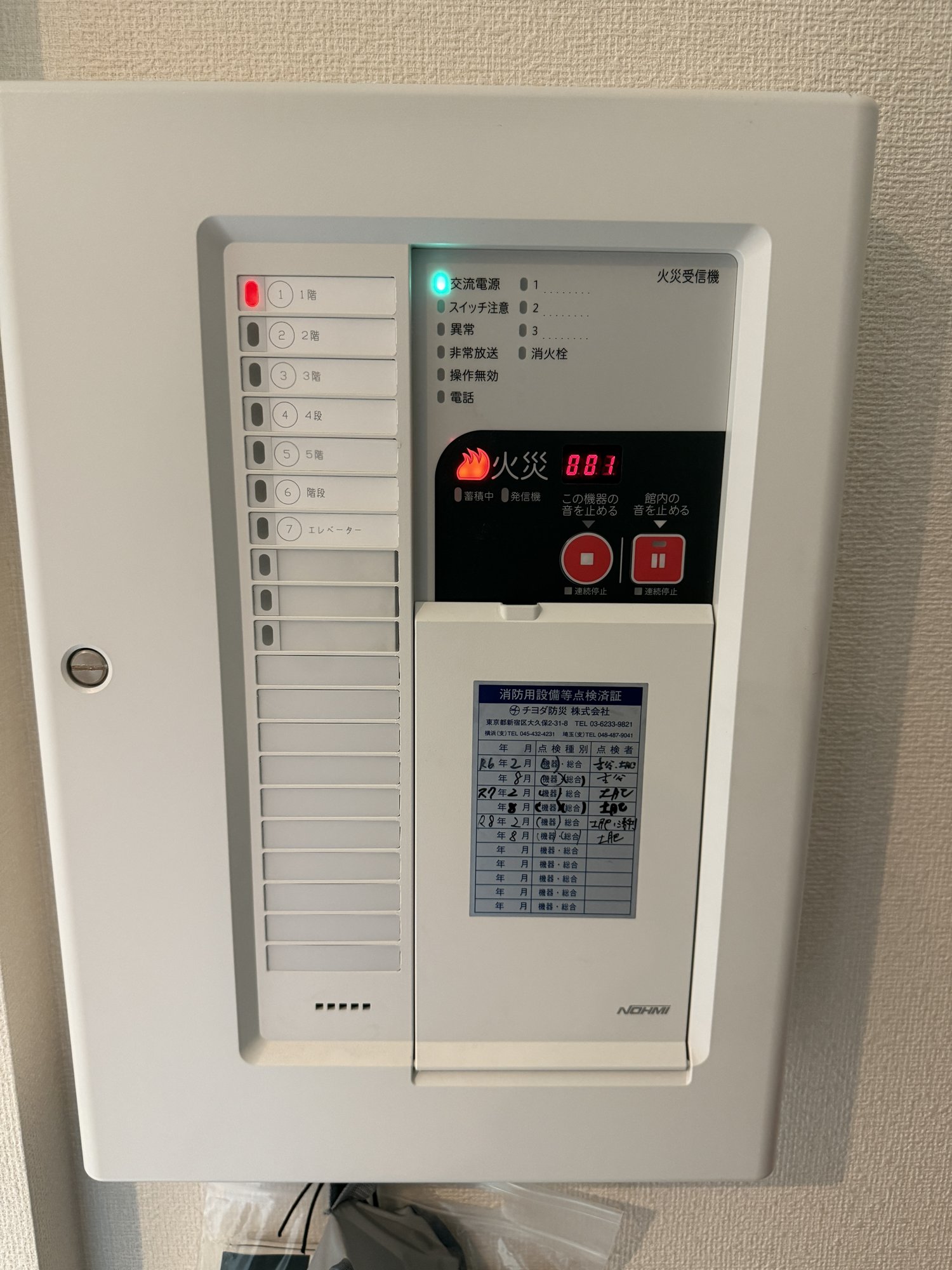 火災信号を受けた状態の受信機。左の「1階」の窓が赤く光り、火災ランプが点灯して数字表示に003と出ている