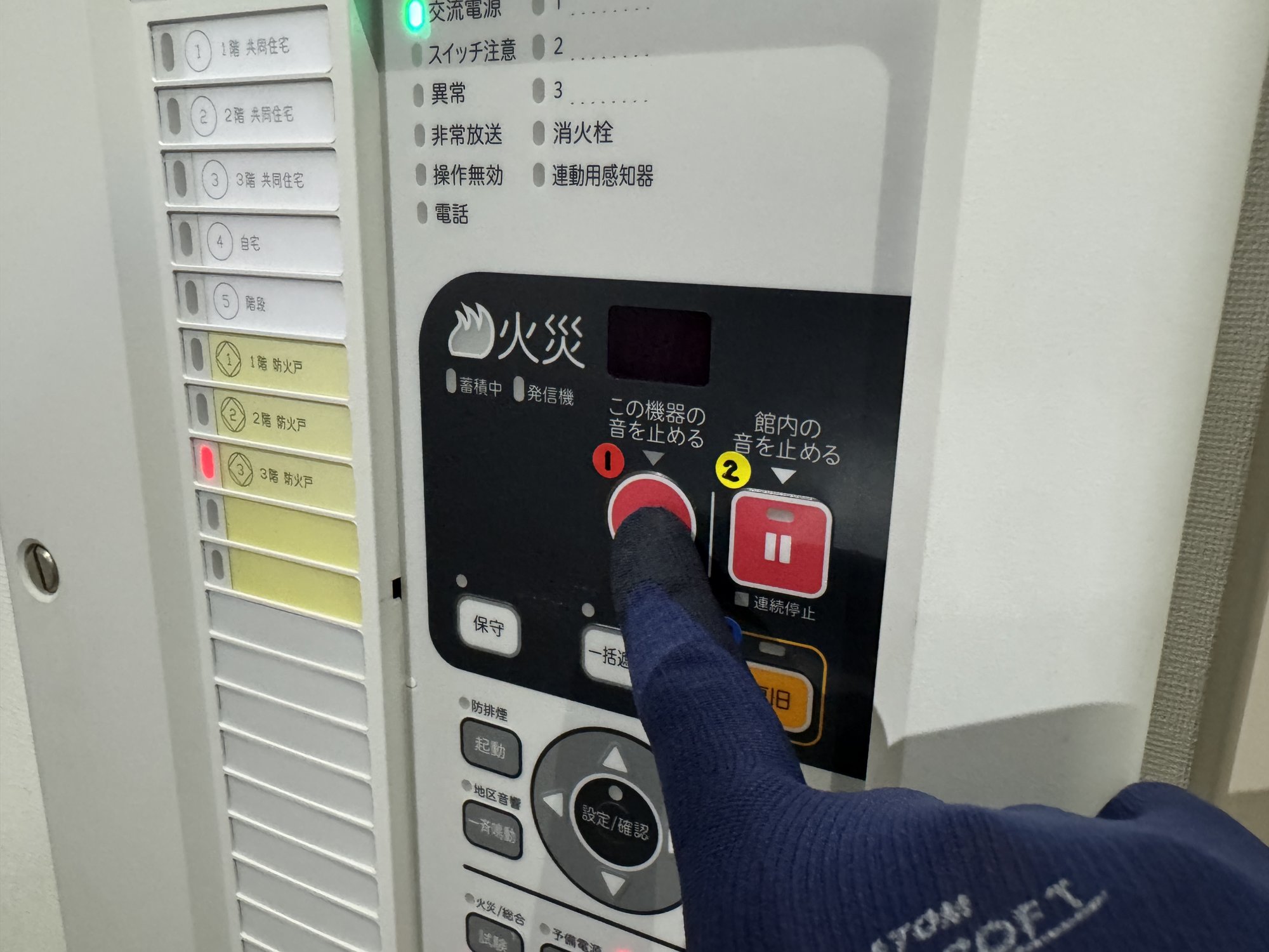 ①「この機器の音を止める」の赤い丸ボタンを指で押しているところ