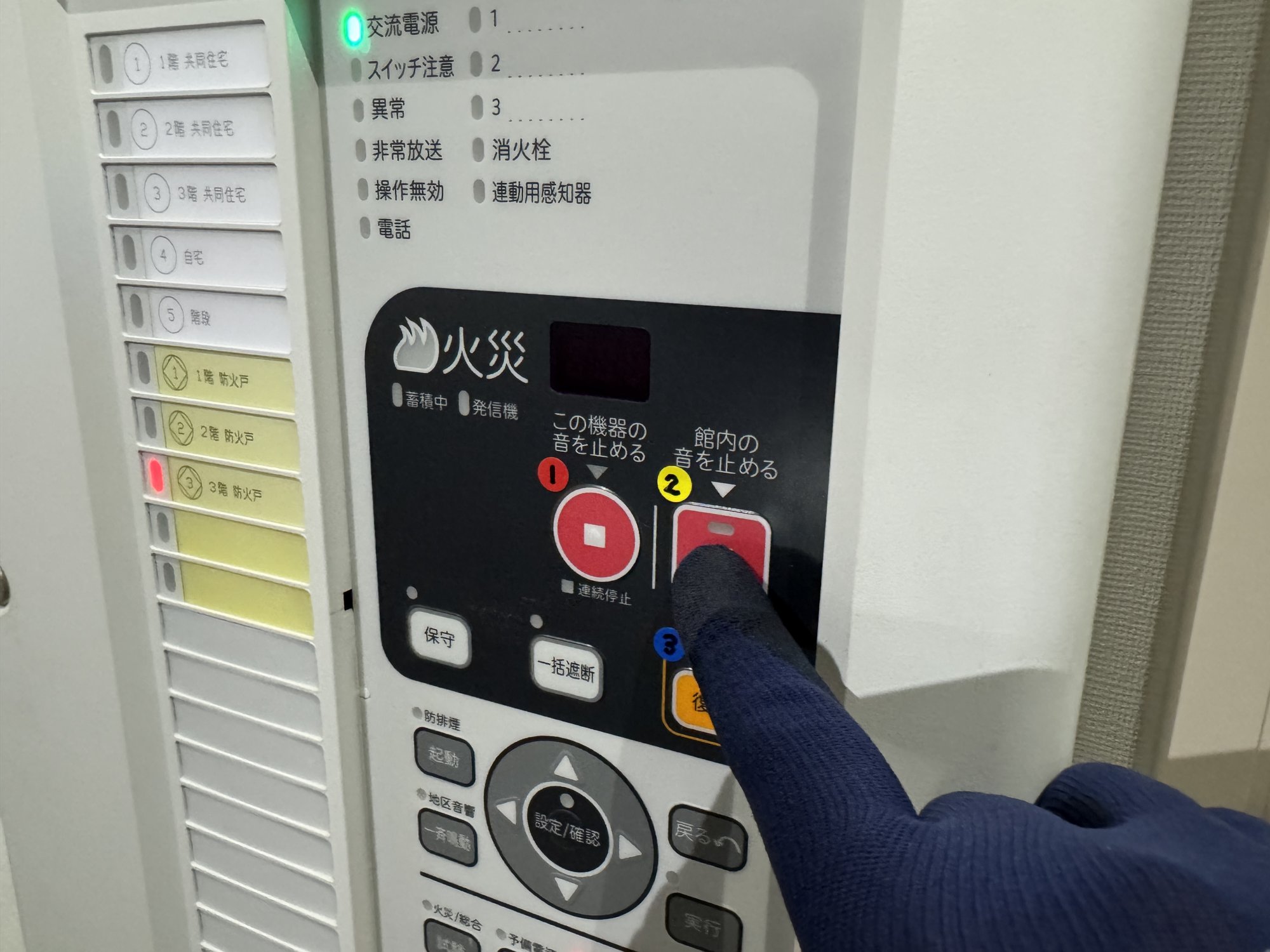 ②「館内の音を止める」の赤い四角ボタンを指で押しているところ